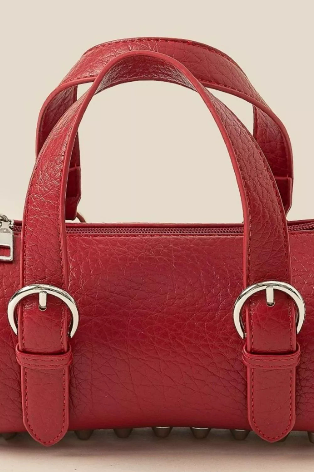 Close-up of a cherry red leather mini handbag with silver-tone buckle hardware and double handles
