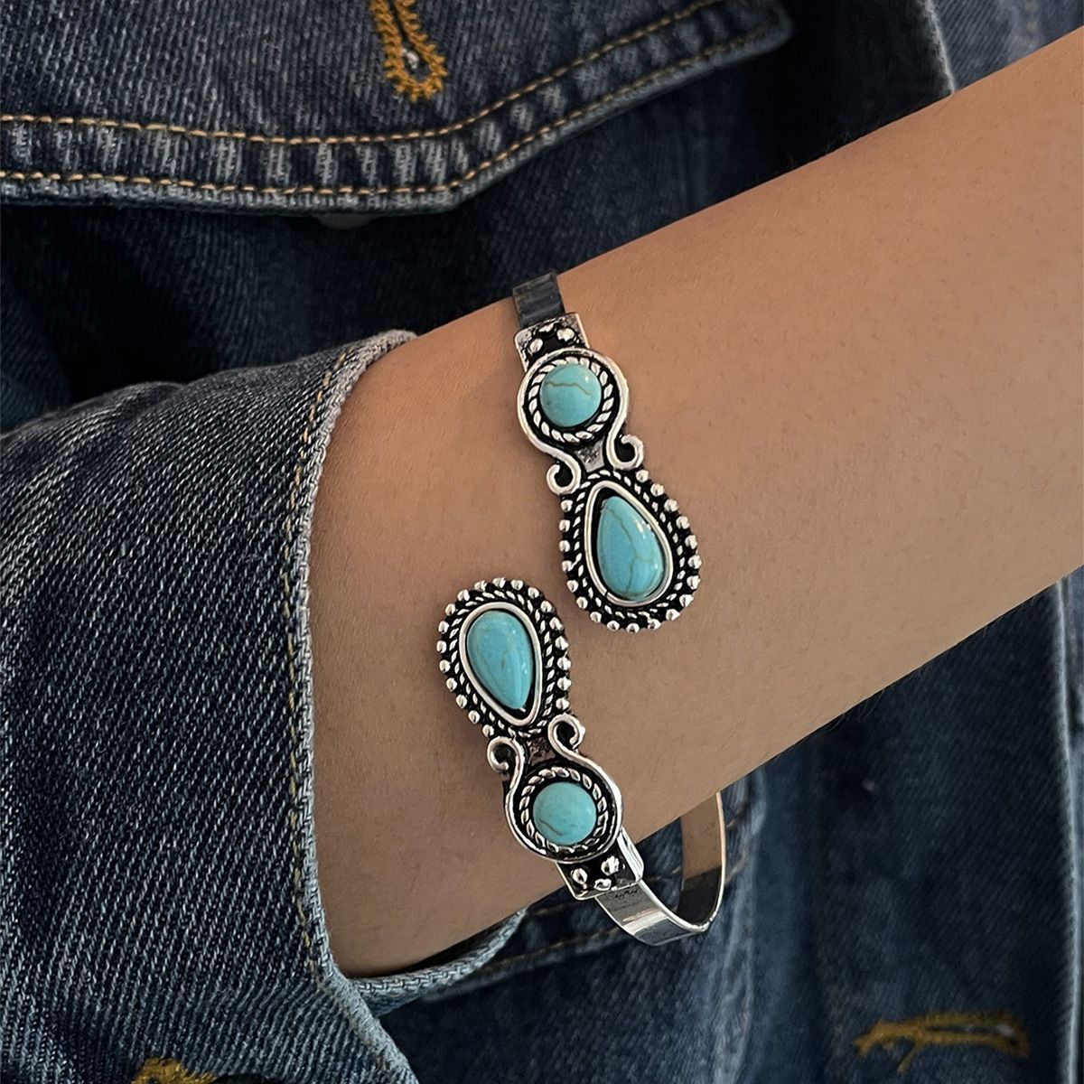 Turquoise open-ended bracelet in silver with rope-edged frames and teardrop turquoise stones.