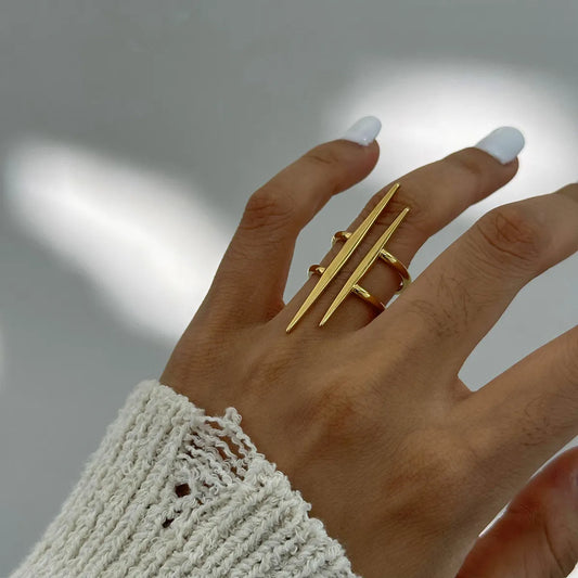 Close-up of a hand wearing a gold-plated stainless steel asymmetrical ring with a modern design.