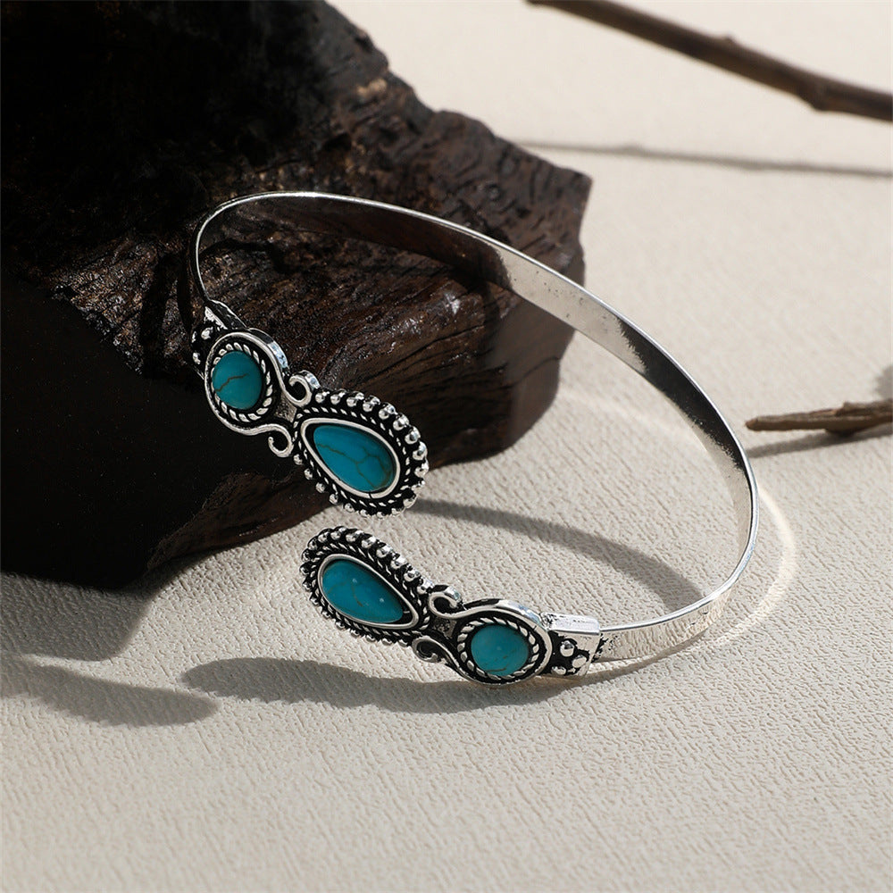 Turquoise open-ended bracelet featuring three turquoise cabochons in silver-tone ornate bezels, ethnic style.